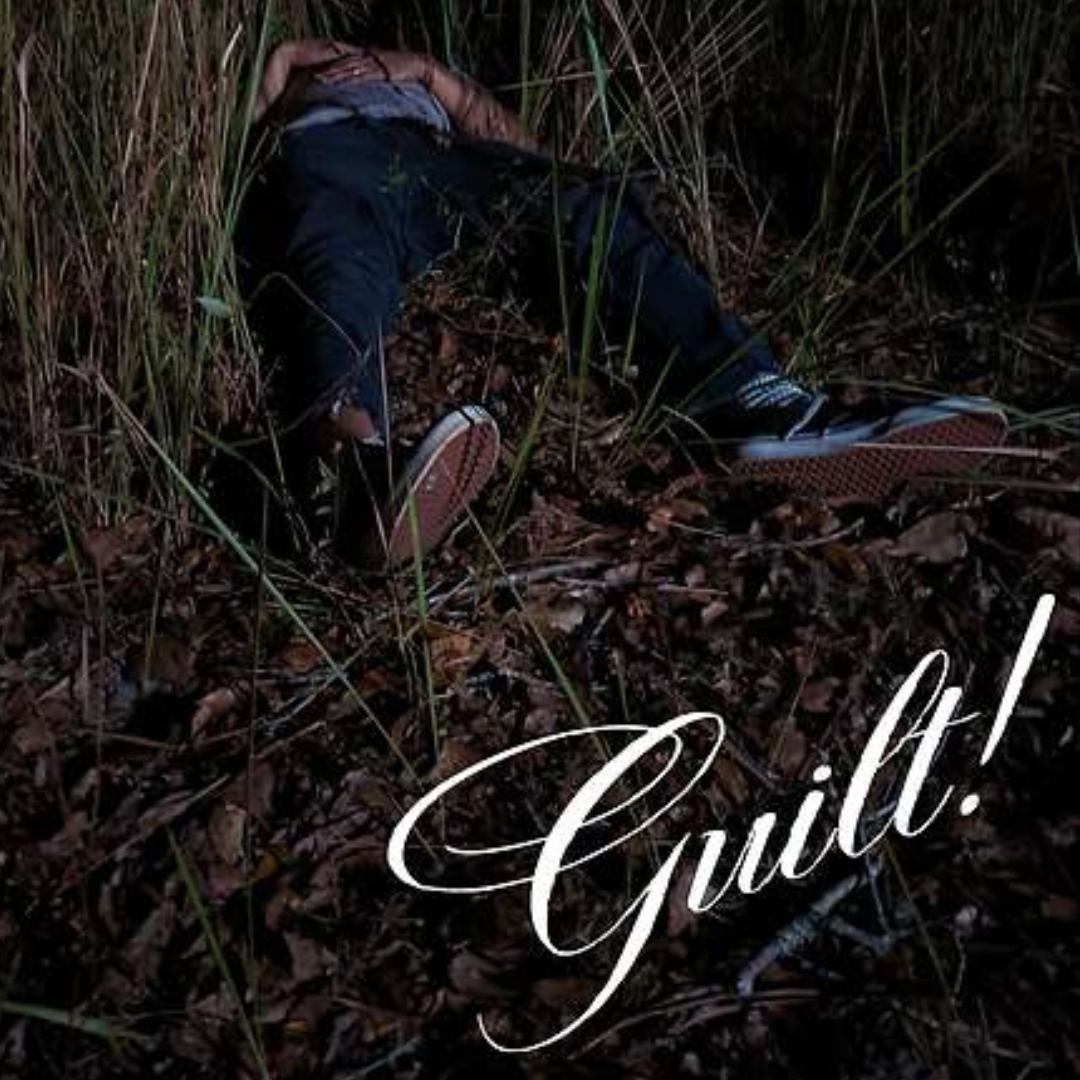 A man lays on his back in a patch of long grass, with his hands on his stomach.